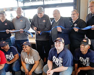 David Fedor, center, the general manager of the new Raising Cane’s in Boardman, cuts the ribbon while surrounded by Raising Cane’s employees and the Boardman Township trustees in the new restaurant on Tuesday. The company has brought 120 jobs to Boardman. 