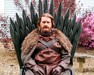 Sam Fleming, 56, of Canfield takes his place upon “the Iron Throne,” which he built from recycled pallet wood, ahead of his family’s watch party for the finale of the hit HBO series Game of Thrones on Sunday. Fleming is dressed as Ned Stark, and other partygoers plan to dress as their favorite character.