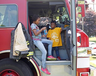 Traeh Lewis, 11, left, and Minnie Smith, 6, both of Youngstown, eat potato chips in the front of a Youngstown firetruck at Kids to Parks Day at Ipe Field on Saturday afternoon. EMILY MATTHEWS | THE VINDICATOR