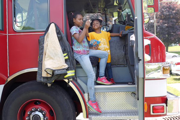 Traeh Lewis, 11, left, and Minnie Smith, 6, both of Youngstown, eat potato chips in the front of a Youngstown firetruck at Kids to Parks Day at Ipe Field on Saturday afternoon. EMILY MATTHEWS | THE VINDICATOR