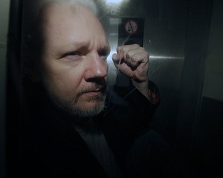 In this May 1, 2019, file photo, WikiLeaks founder Julian Assange puts his fist up as he is taken from court in London. The Justice Department has charged Assange with receiving and publishing classified information. The charges are contained in a new, 18-count indictment announced May 23, 2019.