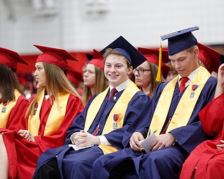 Matthew Bodnark, center, smiles as he listens to his classmates' valedictorian speeches during the Austintown Fitch commencement ceremony in the school's gymnasium Saturday morning. EMILY MATTHEWS | THE VINDICATOR