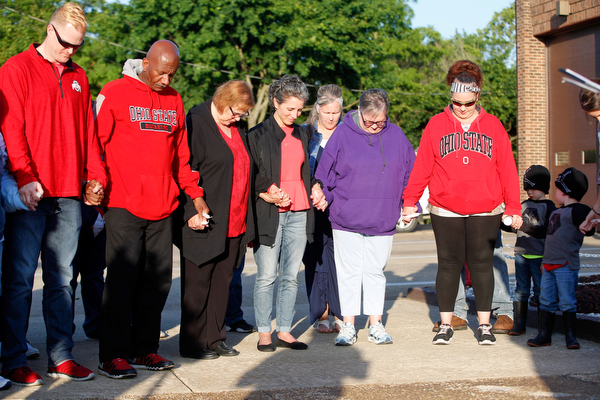 People who are gathered for a vigil to honor Brad and Jacob Crist, who died in a house fire in Niles last week, bow their heads during a prayer at the Niles Safety-Service Complex on Sunday evening. EMILY MATTHEWS | THE VINDICATOR