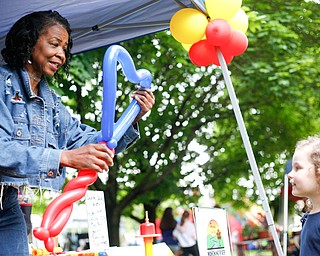 Claudeen Davidson, left, of Colorful Balloons By Design, based in Warren, ties a balloon heart for Harmony Brady, 3, of Austintown, at Riverfest on Sunday afternoon. EMILY MATTHEWS | THE VINDICATOR