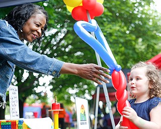 Claudeen Davidson, left, of Colorful Balloons By Design, based in Warren, hands a balloon to Harmony Brady, 3, of Austintown, at Riverfest on Sunday afternoon. EMILY MATTHEWS | THE VINDICATOR