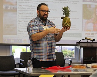 Neighbors | Abby Slanker.Canfield library adult librarian Stuart Gibbs explained how to pick a ripe pineapple during Pineapple Cake Day on April 24.