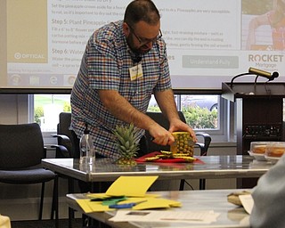 Neighbors | Abby Slanker.Stuart Gibbs, Canfield library adult librarian, demonstrated how to properly cut a pineapple during Pineapple Cake Day on April 24.