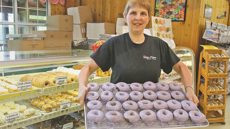 Debbie Pifer, whose family owns White House Fruit Farm in Green Township, holds a tray of the farm’s iconic blueberry doughnuts. Friday is National Doughnut Day, and several Mahoning Valley pastry shops are giving away or offering discounts on the sweet treats.