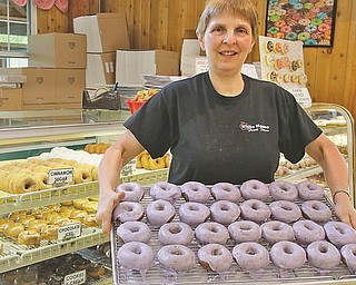 Debbie Pifer, whose family owns White House Fruit Farm in Green Township, holds a tray of the farm’s iconic blueberry doughnuts. Friday is National Doughnut Day, and several Mahoning Valley pastry shops are giving away or offering discounts on the sweet treats.