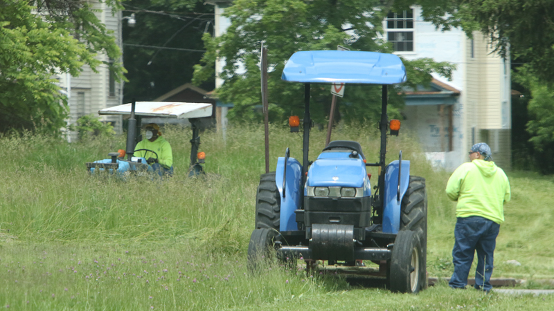 Youngstown Street Department workers cut grass Friday on a vacant lot at Chalmers Avenue and Erie Street on the South Side. The department has cut grass at 3,349 vacant lots in the city. 