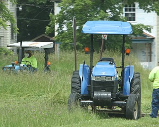 Youngstown Street Department workers cut grass Friday on a vacant lot at Chalmers Avenue and Erie Street on the South Side. The department has cut grass at 3,349 vacant lots in the city. 