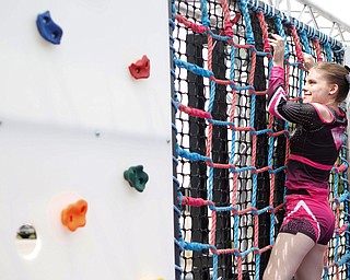 Reygan Long, 17, climbs on a rope and rock wall, part of a ninja obstacle course, during the Autism Warrior Event at the Canfield Fairgrounds on Saturday. She completed the course with her twin sister Kamryn, both of whom have autism and cheer with Miss Dana's Diamonds. EMILY MATTHEWS | THE VINDICATOR
