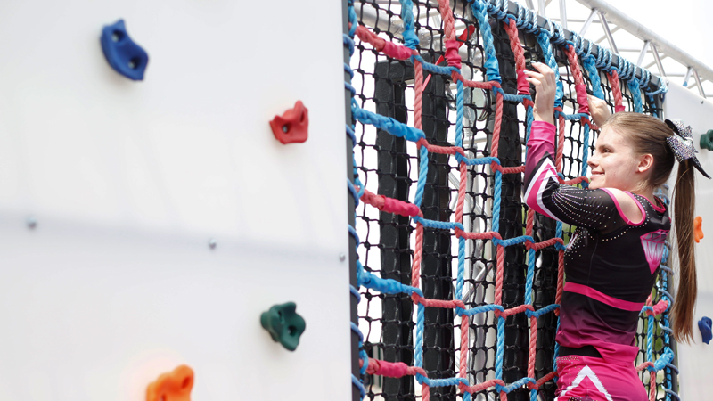 Reygan Long, 17, climbs on a rope and rock wall, part of a Ninja obstacle course, during the Autism Warrior Competition at the Canfield Fairgrounds. She completed the course Saturday with her twin sister Kamryn, both of whom have autism and cheer with Miss Dana's Diamonds. 