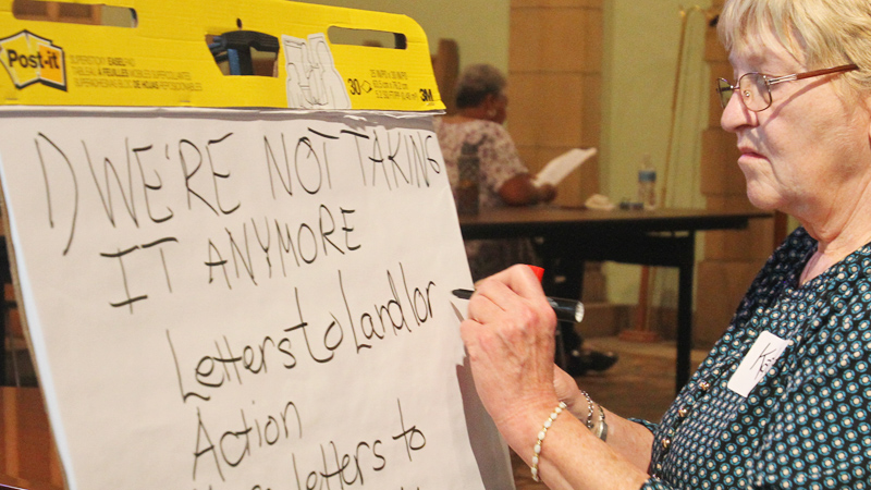 Alliance for Congregational Transformation Influencing Our Neighborhoods scribe Kate Renfield writes down comments made during an ACTION meeting aimed at holding “negligent landlords” accountable. The meeting was Tuesday night at Martin Luther Lutheran Church on the South Side. 