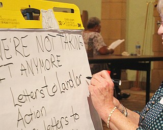 Alliance for Congregational Transformation Influencing Our Neighborhoods scribe Kate Renfield writes down comments made during an ACTION meeting aimed at holding “negligent landlords” accountable. The meeting was Tuesday night at Martin Luther Lutheran Church on the South Side. 