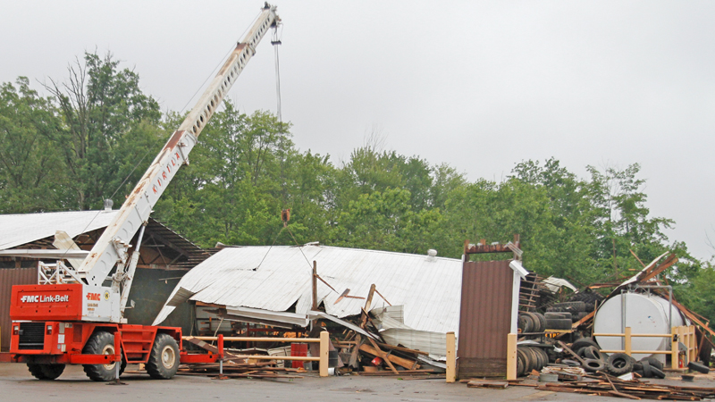 A worker on a forklift on Monday moves items under a collapsed building on the Kirila Construction Co. property in Brookfield caused by Sunday's tornado. The building had housed some heavy machinery and tires.