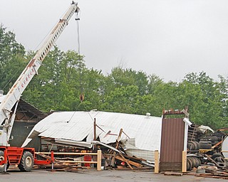 A worker on a forklift on Monday moves items under a collapsed building on the Kirila Construction Co. property in Brookfield caused by Sunday's tornado. The building had housed some heavy machinery and tires.