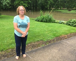 Theresa Barbe of Meadowbrook Street in Leavittsburg stands near chalk markings on her driveway. Barb, who has lived in her home about 20 years, said the marking beside her represents the point where flooding would start to create problems for her basement. The river level rose to 13 feet around 6:30 a.m.  Monday morning, causing the Mahoning River just across the street from her house to flow over her street.