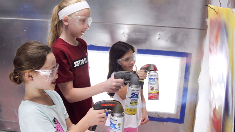 Zana Wooley, 8, of Austintown, left, Kylie Anderson, 9, also of Austintown, and Rosa Pascolini, 7, of Canfield make different designs with spray paint during a science, technology, engineering, arts and mathematics camp sponsored by KTSDI Vehicle Solutions LLC in North Lima. 