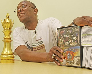 Michael Abron, who hopes to become the first black man to play in United States Chess Federation tournaments in all 50 states, shows a book that details his adventures across the country.