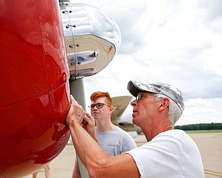 Neighbors Casey Dickson, right, and Cliff Phillips, 15, both of Warren, look at the front of an AT6 that WASPs flew at the Warren Regional Airport on Wednesday. The AT6 and a B-29 and were at the airport for people to look at and learn about. Dickson said he is going to be flying the AT6 tomorrow afternoon. EMILY MATTHEWS | THE VINDICATOR