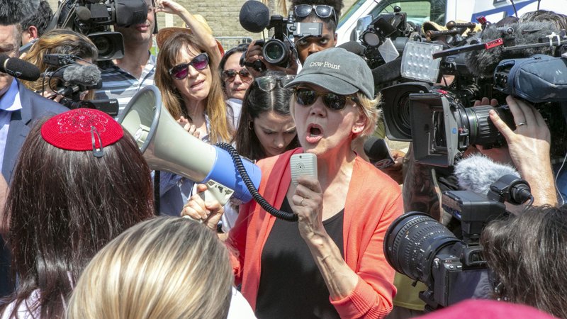 Democratic presidential candidate Sen. Elizabeth Warren, D-Mass., speaks through a megaphone while surrounded by the media outside the Homestead Detention Center, where the U.S. is detaining migrant teens, in Homestead, Fla., Wednesday.