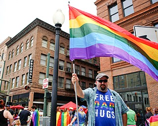 Michael Amedio, of East Liverpool, holds a pride flag and wears a shirt that reads Free Dad Hugs at the 11th annual Pride parade and festival in downtown Youngstown on Saturday afternoon. Amedio said he wore the shirt as a message of support that some people in the LGBTQ do not receive from their parents. EMILY MATTHEWS | THE VINDICATOR