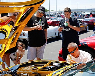 From left, Gianna Varie, 4, Dean Varie, and Carter Nice, 12, all of Struthers, look at Rex Swortzbeck's 2003 Chevrolet Corvette while Swortzbeck, bottom right, of Greenville, Pa., puts a chrome plate behind one of his wheels at the Mahoning Valley Corvette Club's 25th Annual Corvette and Steel Car Show at Greenwood Chevrolet in Austintown on Sunday. EMILY MATTHEWS | THE VINDICATOR