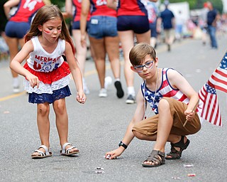 Siblings Lena Miller, 6, and Dominick Miller, 9, of Warren, pick up candy during the Austintown Fourth of July parade on Raccoon Road Thursday afternoon. EMILY MATTHEWS | THE VINDICATOR