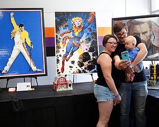 From left, Abbey and Steve Stiles and their 7-month-old daughter Freya, all of Austintown, take a selfie in front of pieces made by members of NeoLUG, a group of adult hobbyists who share their passion for building with Legos, at the Youngstown Comic Con in Covelli Centre on Saturday afternoon. EMILY MATTHEWS | THE VINDICATOR