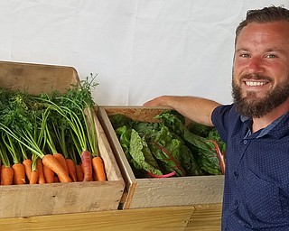 Parker Maynard, director of the GROW Urban Farm at Flying High Inc., displays some fresh-picked vegetables during the garden’s market day.