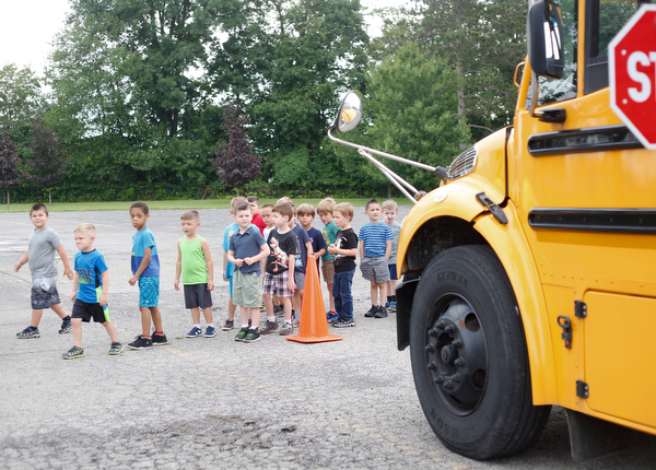 Incoming kindergarteners use what they learn about bus safety to cross in front of a bus as part of United Way's Success By 6 program at Stadium Drive Elementary on Tuesday morning. EMILY MATTHEWS | THE VINDICATOR