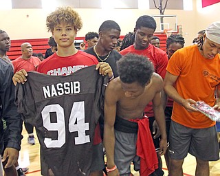 Chaney High School football player Christian Jones, center, holds up a Cleveland Browns jersey. Representatives of the NFL team visited Chaney on Monday morning and provided the Cowboys cleats, pants, gloves and both used game and practice jerseys as part of the Browns’ Huddle for 100 program. At left is Chaney head coach Chris Amill.