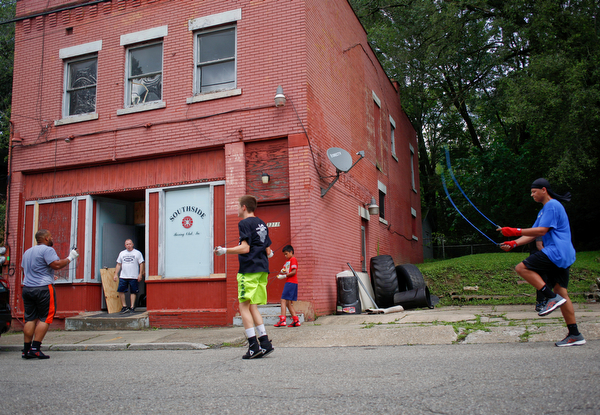 Jack Loew watches from the entrance of his boxing club as, from left, Bryan Gonzalez, Jackson Behun, Juan Jauregui, 10, and Deven Tate, all members of the Boxing Club, jump rope outside the club on Erie Street on Monday. EMILY MATTHEWS | THE VINDICATOR