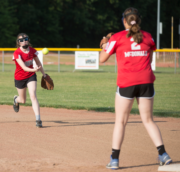 Emma Wolfe, left, tosses the ball to Katie McDonald at first as they practice with their Canfield-Poland softball team, who will be playing in the Junior League Softball World Series in Washington on Sunday. EMILY MATTHEWS | THE VINDICATOR