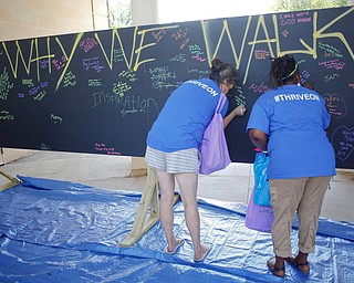 Tasha Dore, left, and Bianca Lynn, both of Cleveland and with the organization Thrive, write why they walk in the Warren Walk Against Heroin on a blackboard at the Warren Amphitheater on Sunday. EMILY MATTHEWS | THE VINDICATOR