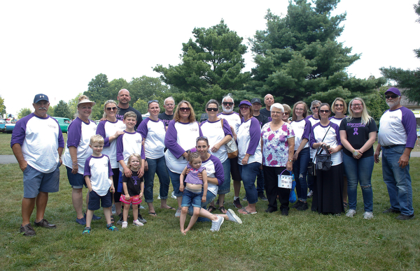 Jade Foley, of Cortland, front center, holds her daughter Harper Foley, 4, who has Dravet Syndrome, a catastrophic form of epilepsy, while family members and friends stand behind them at the 41st annual Cars in the Park car show in Boardman Park on Sunday afternoon. Proceeds from the car show will go to Harper. EMILY MATTHEWS | THE VINDICATOR