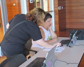 Neighbors | Jessica Harker .Samantha Schneider, a librarian at the Michael Kusalaba library, helped community members design patterns to engrave on a mason jar glass July 1.