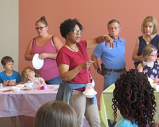 Neighbors | Jessica Harker .Children's librarian Rhonda Monroe explained three space themed crafts to community members gathered at the Space Invaders Craft event at the Michael Kusalaba library.