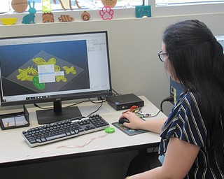 Neighbors | Jessica Harker .Hannah Matulek selected designs chosen by community members to print using the library's 3D printer at the first Outer Space Jewlery making event July 10.