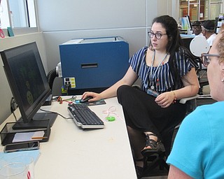 Neighbors | Jessica Harker .Librarian Hannah Matulek worked with community members to personalize designs on space theme necklaces at the Michael Kusalaba library July 10.