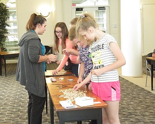 Neighbors | Jessica Harker .Tweens and teenagers walked through a line selecting supplies to create a shark tooth necklace with the help of librarian Renee Beverly July 29.