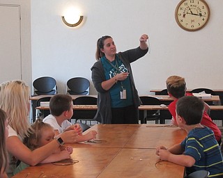 Neighbors | Jessica Harker .Librarian Renee Beverly demonstrated how to construct a shark took necklace at the Austintown library July 29.