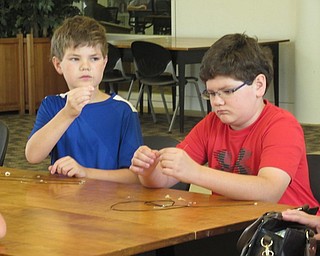 Neighbors | Jessica Harker .Children used wire to wrap shark teeth to hang on necklaces July 29 at the Austintown library in celebration of Shark Week.
