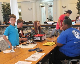 Neighbors | Jessica Harker .Tech Corp instructor Maia Pickens works with middle school students on Aug. 8 at the Austintown library for the library's first Techie Corp.