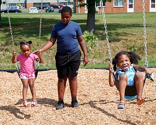 Amyre Milender, 11, center, pushes Danyla Abdullah, 2, left, and Aries Baity, 4, on the swings at the new playground at Lincoln Knolls Community Park on Saturday.  EMILY MATTHEWS | THE VINDICATOR