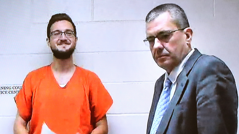 James Reardon, left, smiles as he is arraigned via video Monday in Struthers Municipal Court on charges he threatened to shoot up the Jewish Community Center in Youngstown. He was ordered held on 10 percent of $250,000 bond. To the right is Atty. Walter Ritchie, who represents clients who appear for arraignments via video hookup from the jail.