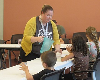 Neighbors | Jessica Harker .Librarian Amelia Dale helped children create their own miniature shark tanks at the Michael Kusalaba library's crafting event July 30.