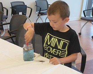 Neighbors | Jessica Harker .Logan Amaismeier stirred glitter into his mini shark tank at the crafting event hosted by the Michael Kusalaba library July 30.