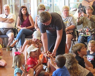 Neighbors | Jessica Harker .Volunteer Noah walked around the Michael Kusalaba library allowing community members to pet a snake brought by Mark Kohlhorst July 29 during Mark's Ark live animal show.